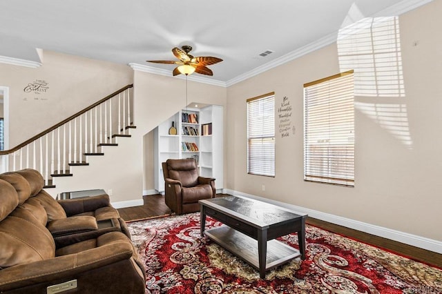 living area featuring wood finished floors, crown molding, stairs, baseboards, and ceiling fan