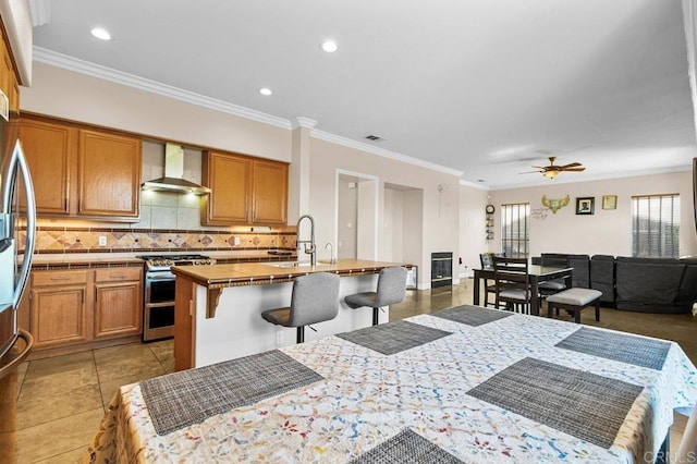 kitchen with stainless steel appliances, wall chimney range hood, open floor plan, a kitchen breakfast bar, and tasteful backsplash