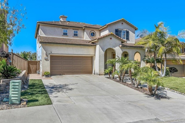 mediterranean / spanish house with driveway, fence, a chimney, and stucco siding