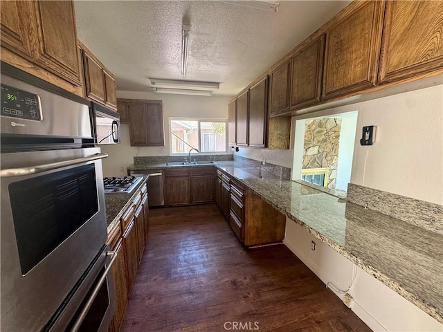 11536 Cimarron Ave, Hawthorne, CA 90250 - kitchen featuring a textured ceiling, dark wood-type flooring, appliances with stainless steel finishes, a sink, and dark stone counters