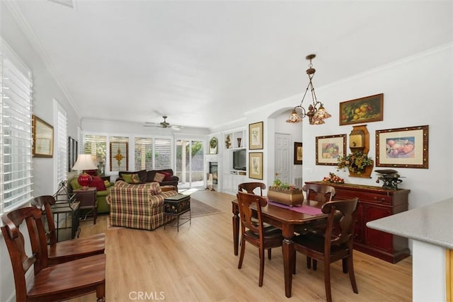 24247 Songsparrow Ln, Corona, CA 92883 - dining room with a ceiling fan, light wood-type flooring, crown molding, arched walkways, and a fireplace