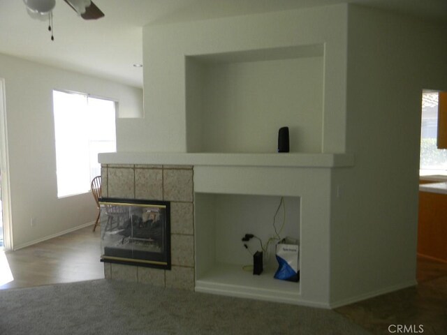 613 Big Spring Dr, Banning, CA 92220 - unfurnished living room featuring a tiled fireplace, ceiling fan, carpet flooring, and baseboards