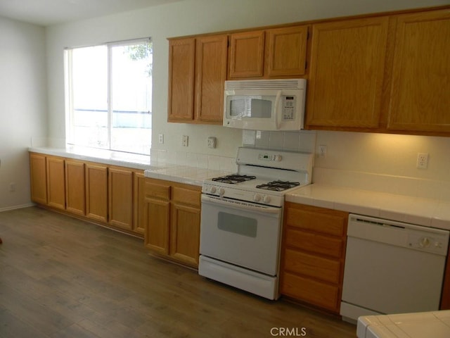 613 Big Spring Dr, Banning, CA 92220 - kitchen with white appliances, tile counters, wood finished floors, and brown cabinetry