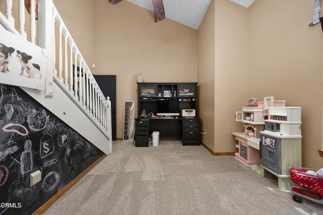 carpeted home office with ceiling fan, baseboards, and high vaulted ceiling