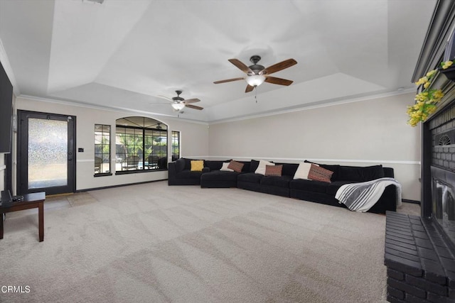 carpeted living area featuring a tray ceiling, ornamental molding, and a ceiling fan