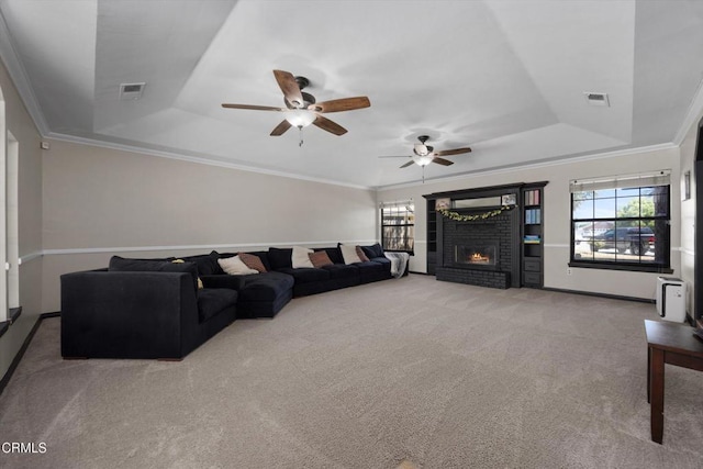 living area featuring a tray ceiling, healthy amount of natural light, carpet flooring, and crown molding