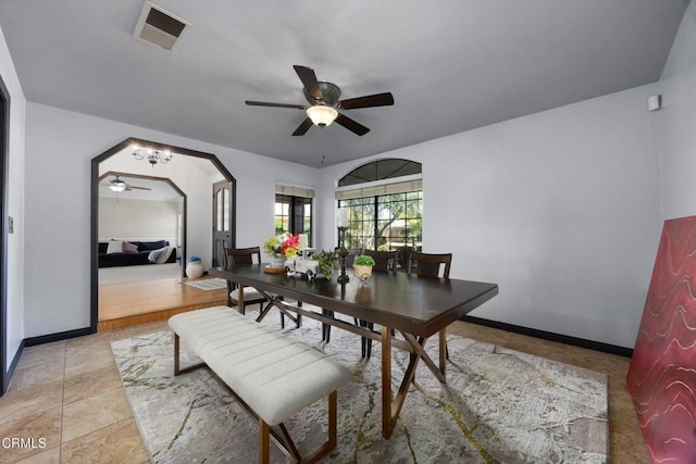 dining space with a ceiling fan, baseboards, and arched walkways