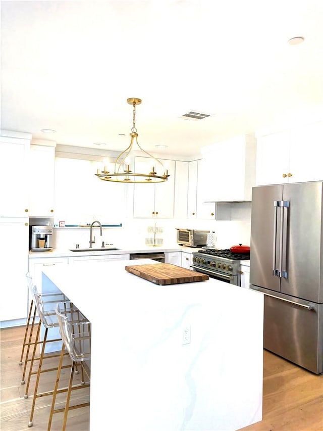 2621 Gates Ave Unit B, Redondo Beach, CA 90278 - kitchen featuring premium appliances, a sink, a kitchen island, a chandelier, and white cabinetry