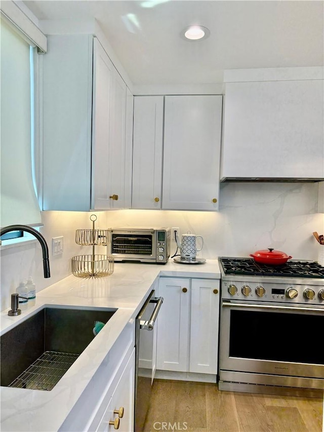 2621 Gates Ave Unit B, Redondo Beach, CA 90278 - kitchen featuring appliances with stainless steel finishes, a sink, white cabinetry, light wood-style flooring, and backsplash