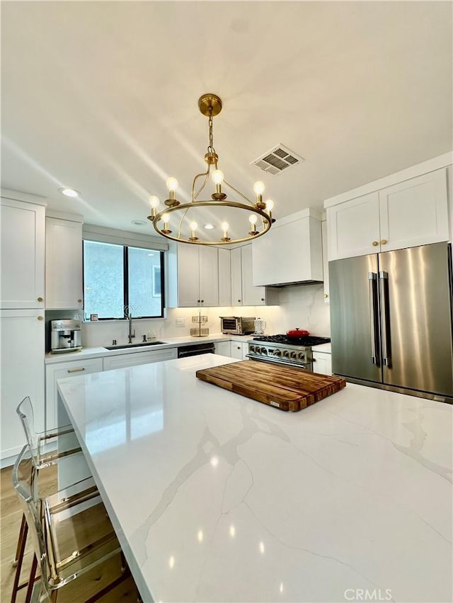 2621 Gates Ave Unit B, Redondo Beach, CA 90278 - kitchen featuring premium appliances, a sink, a chandelier, light stone countertops, and white cabinetry