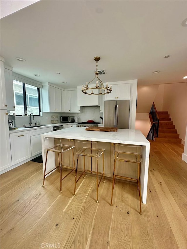 2621 Gates Ave Unit B, Redondo Beach, CA 90278 - kitchen with high quality fridge, light wood finished floors, white cabinets, a sink, and a large island