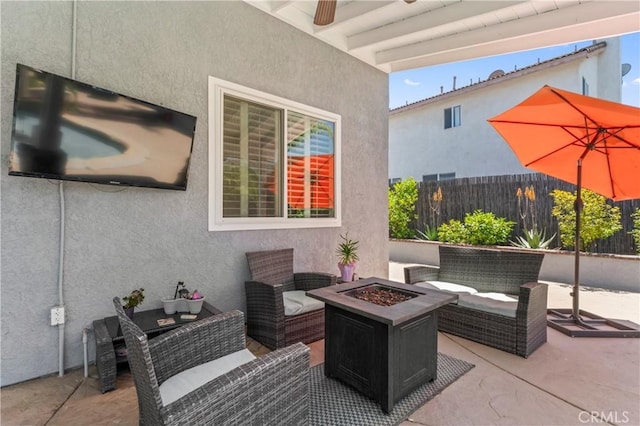view of patio featuring fence, a ceiling fan, and an outdoor living space with a fire pit