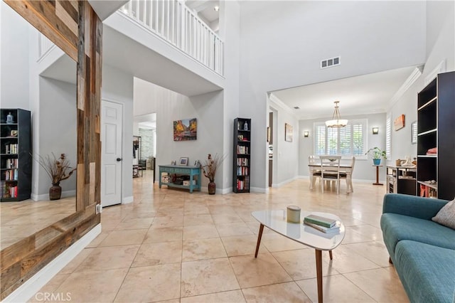 living area featuring crown molding, a high ceiling, a chandelier, light tile patterned flooring, and baseboards