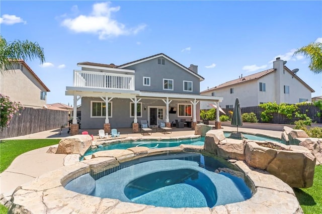 back of property with a fenced backyard, a patio area, a balcony, and a pool with connected hot tub