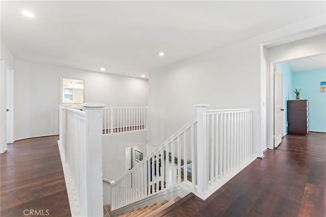 hallway with an upstairs landing, wood finished floors, and recessed lighting