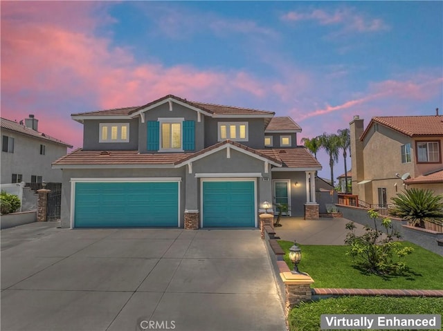 view of front of house with driveway, a garage, stucco siding, a yard, and a tiled roof