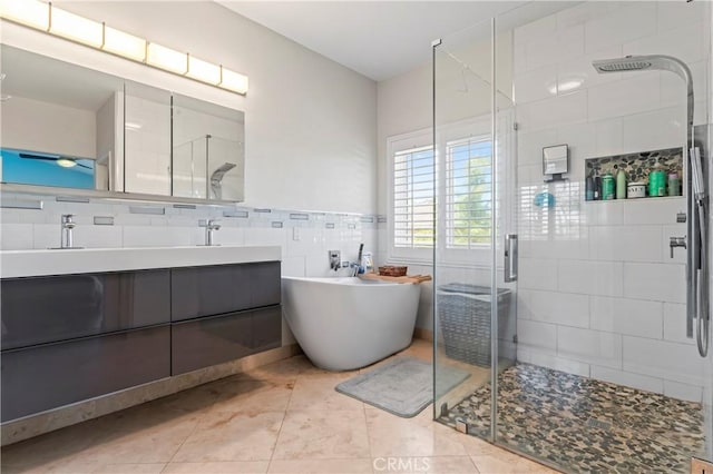 bathroom with tile walls, a stall shower, a freestanding tub, double vanity, and tile patterned flooring