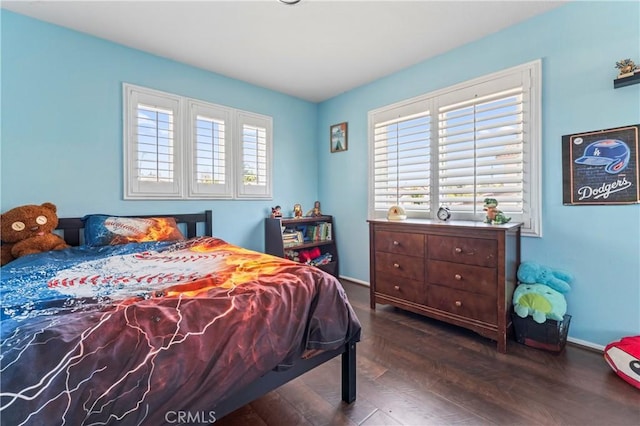 bedroom featuring multiple windows, wood finished floors, and baseboards