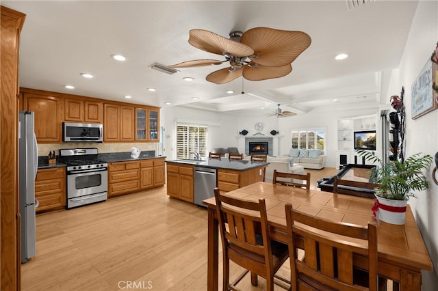 kitchen with stainless steel appliances, a sink, ceiling fan, brown cabinets, and recessed lighting