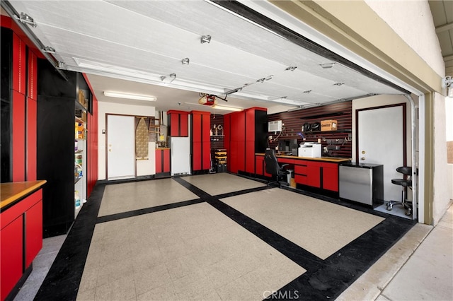 garage with a garage door opener, freestanding refrigerator, and refrigerator