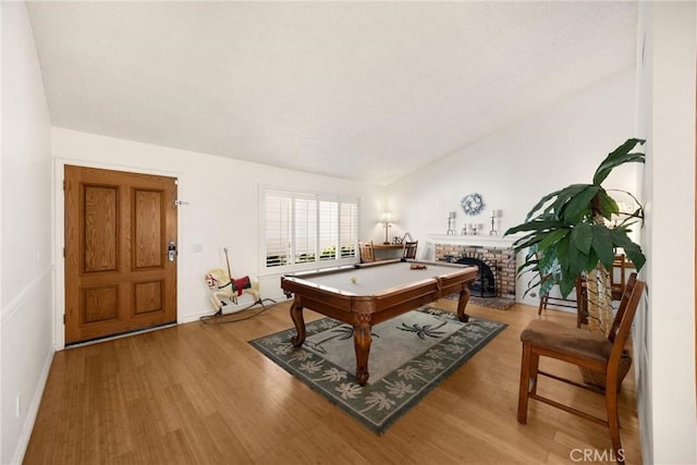 rec room featuring light wood finished floors, baseboards, pool table, a fireplace, and vaulted ceiling