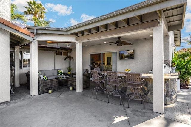view of patio with outdoor lounge area, ceiling fan, and exterior bar