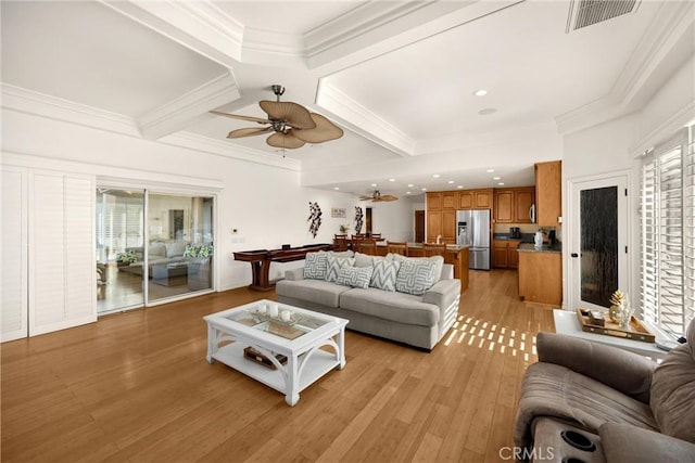 living room featuring light wood-type flooring, crown molding, a ceiling fan, coffered ceiling, and beam ceiling