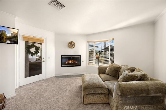 living area with ornamental molding, carpet, a glass covered fireplace, and baseboards
