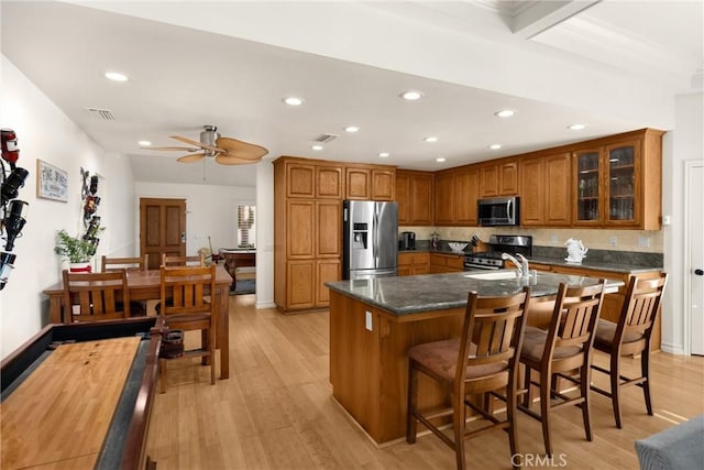 kitchen featuring stainless steel appliances, brown cabinets, recessed lighting, glass insert cabinets, and light wood-style flooring