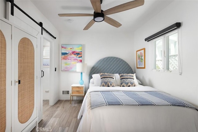 565 Lombardy Ln, Laguna Beach, CA 92651 - bedroom featuring multiple windows, a barn door, light wood-style floors, and a ceiling fan