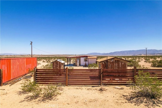 rear view of house with fence, a mountain view, and an outdoor structure
