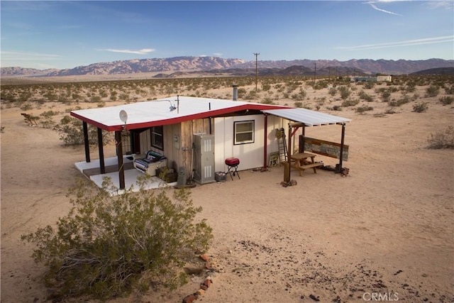 back of property with a desert view, a mountain view, a patio area, and a view of rural / pastoral area