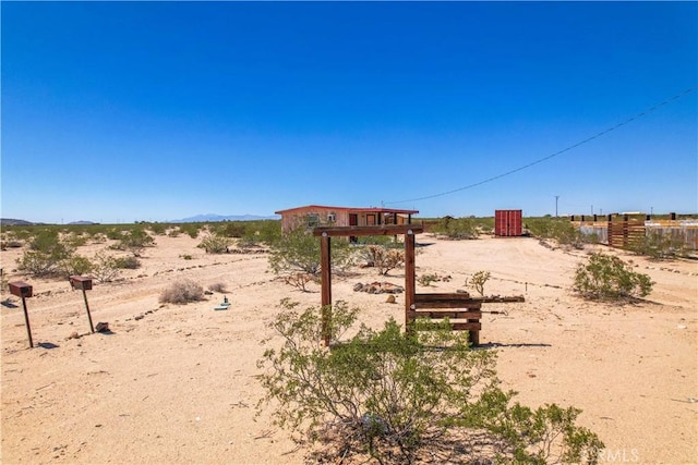 view of yard featuring fence, a view of countryside, and view of desert