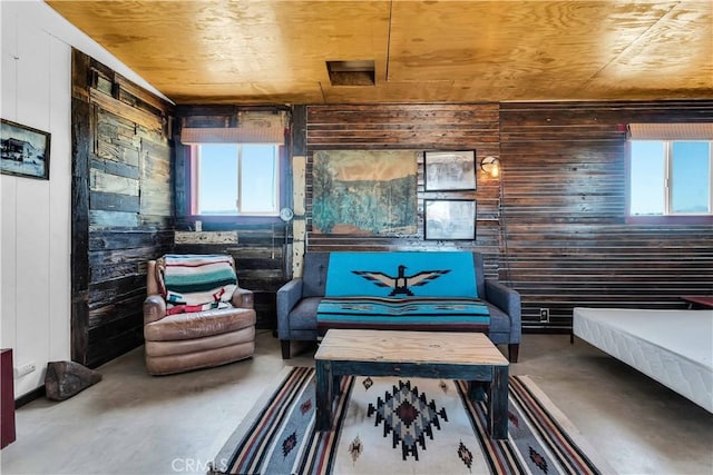 sitting room featuring concrete floors, wood walls, plenty of natural light, and wood ceiling