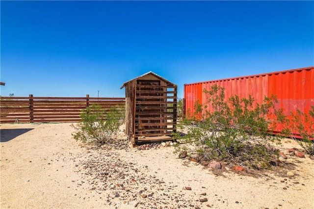 view of outdoor structure with fence and an outbuilding