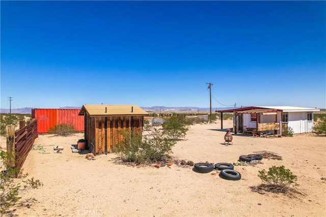 view of yard with a mountain view, an outbuilding, fence, and a storage shed