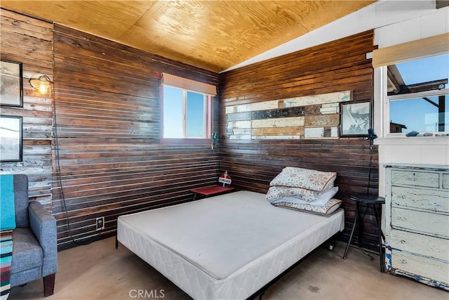 bedroom with wood walls, lofted ceiling, and concrete flooring