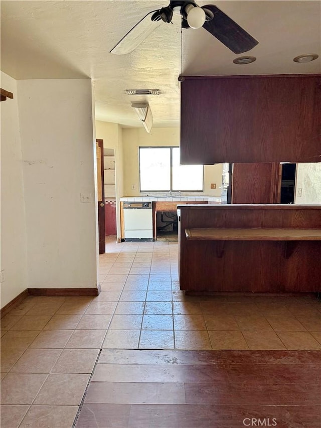kitchen with dishwasher, ceiling fan, light tile patterned flooring, and baseboards