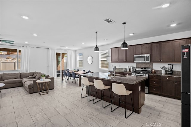 62892 Loftwood St, Desert Hot Springs, CA 92240 - kitchen featuring stainless steel appliances, a sink, open floor plan, a kitchen breakfast bar, and dark brown cabinetry
