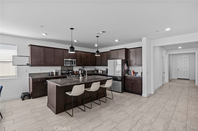 62892 Loftwood St, Desert Hot Springs, CA 92240 - kitchen with appliances with stainless steel finishes, a sink, a breakfast bar area, dark brown cabinetry, and a center island with sink