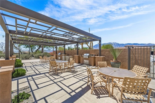 62892 Loftwood St, Desert Hot Springs, CA 92240 - view of patio with an outdoor kitchen, outdoor dining area, a mountain view, and fence