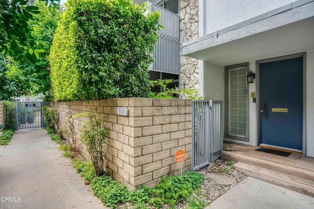 4213 Sarah St Unit 22, Burbank, CA 91505 - view of exterior entry featuring a gate, stucco siding, fence, and stone siding