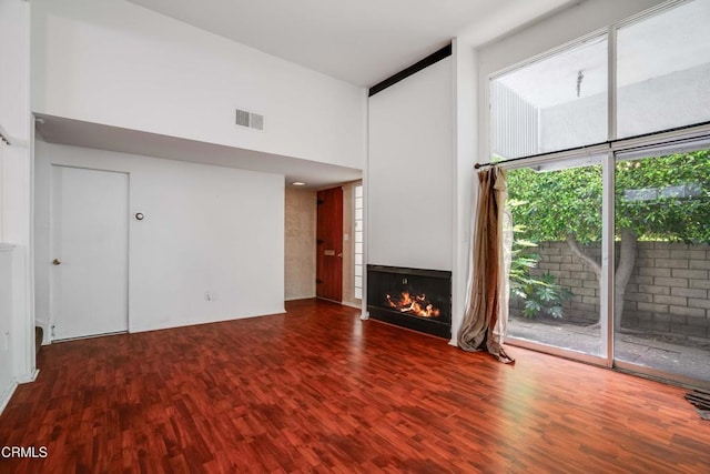 4213 Sarah St Unit 22, Burbank, CA 91505 - unfurnished living room with wood finished floors, a towering ceiling, and a lit fireplace