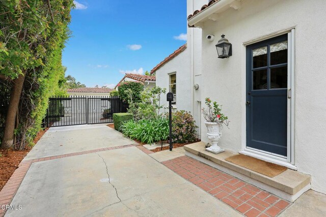 670 San Marino Ave, San Marino, CA 91108 - entrance to property with stucco siding, a tile roof, a surveillance system, and a gate