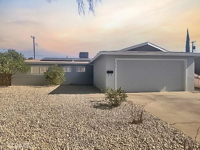 410 Orange Ave, Los Banos, CA 93635 - single story home featuring roof mounted solar panels, concrete driveway, stucco siding, and a garage