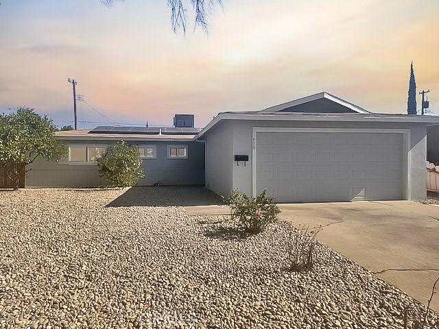 410 Orange Ave, Los Banos, CA 93635 - ranch-style home with solar panels, concrete driveway, stucco siding, and a garage