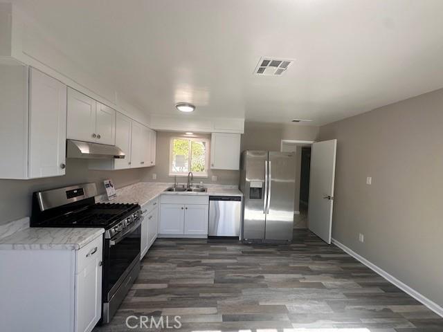 410 Orange Ave, Los Banos, CA 93635 - kitchen with appliances with stainless steel finishes, a sink, under cabinet range hood, white cabinetry, and light countertops