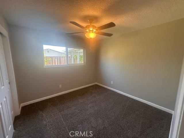 410 Orange Ave, Los Banos, CA 93635 - empty room featuring dark colored carpet, a ceiling fan, and a textured ceiling