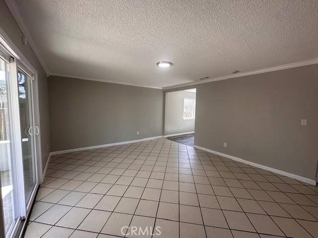 410 Orange Ave, Los Banos, CA 93635 - spare room with crown molding, a textured ceiling, and light tile patterned flooring