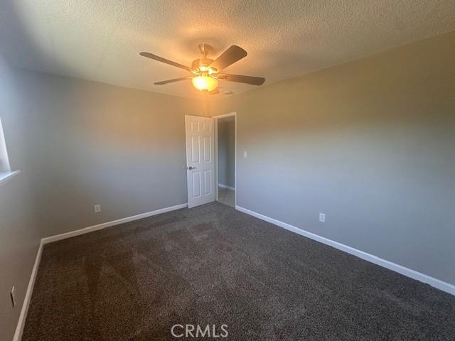 410 Orange Ave, Los Banos, CA 93635 - unfurnished room featuring a ceiling fan, dark colored carpet, a textured ceiling, and baseboards